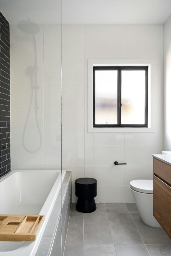 Stylish bathroom with white marble tiles, black accents, and a bathtub.